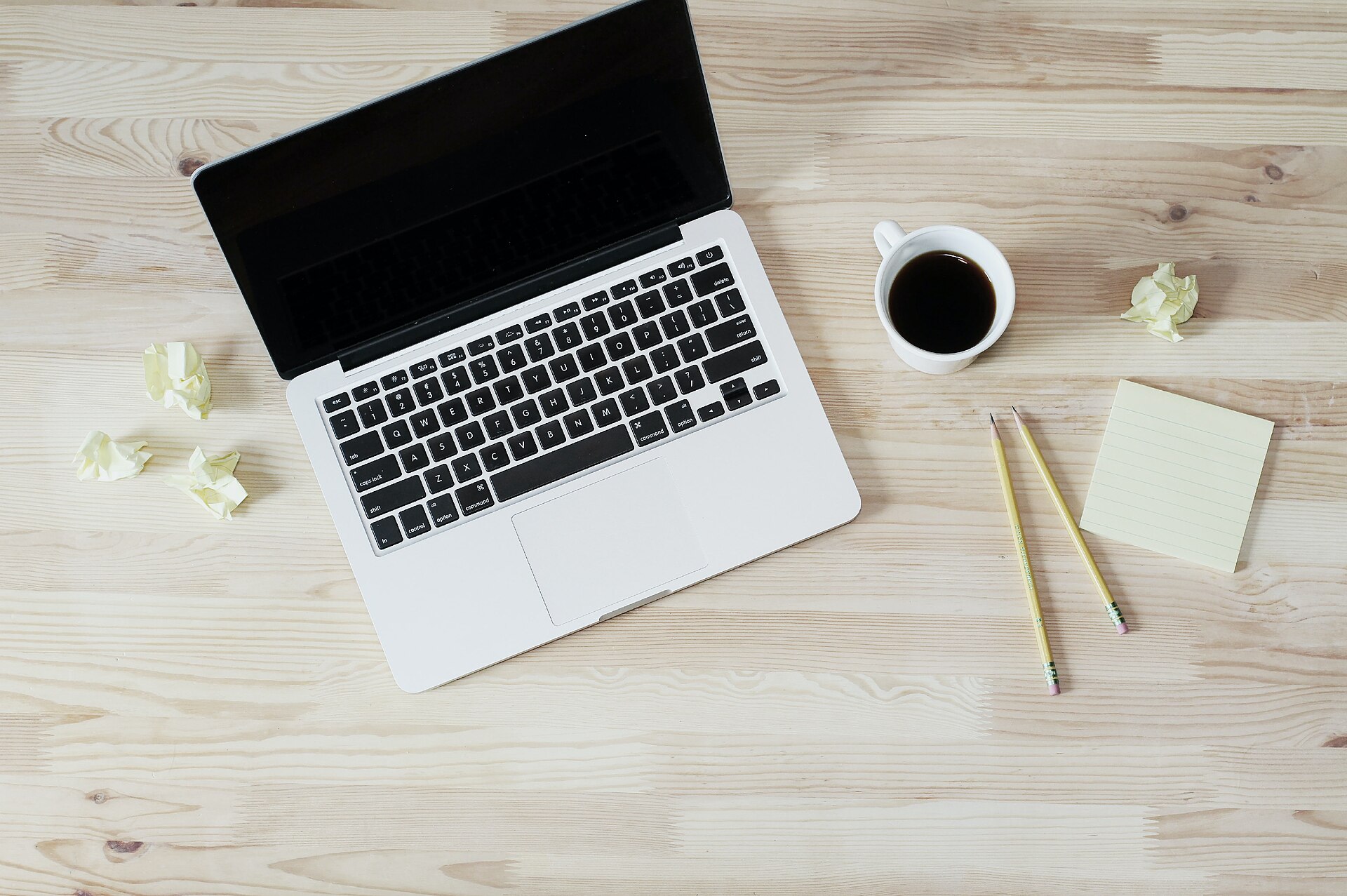 Åben laptop, notesblok og kaffe på et bord til at gennemgå spørgsmål før et hjemmesidetilbud
